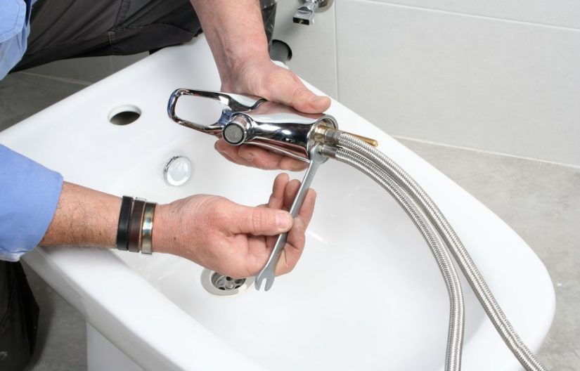 Plumber Installing Faucet On Bidet In Bathroom — Professional Plumbing Services in Roseville, NSW