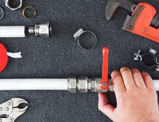 A Person Fixing a Pipe with A Wrench — Professional Plumbing Services in Forestville, NSW